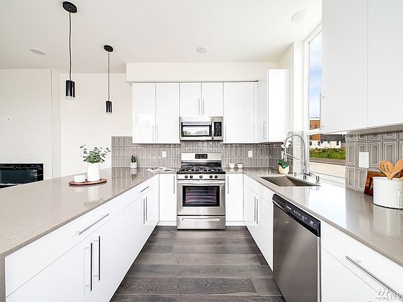 The kitchen has quartz counters and ton of cabinetry, stainless appliances and attractive tile backsplash.