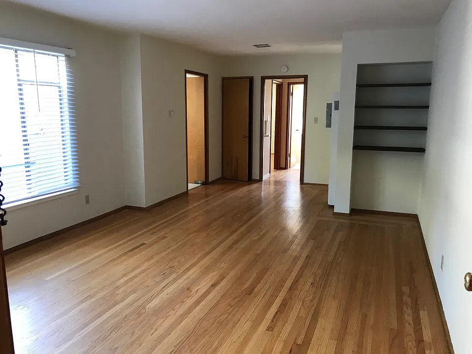 View from the front door, hardwood floors, built in bookshelves and vintage phone nook in the distance