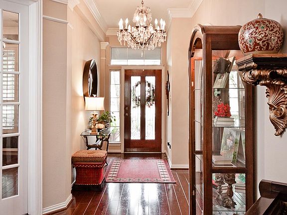 Inviting foyer touts wide-planked hardwood floors, triple crown molding, beautiful leaded glass fron