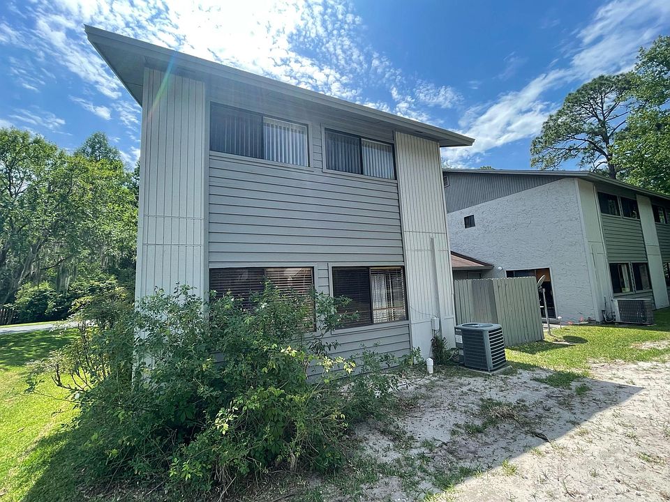 Back of home showing windows overlooking two pools and also the air conditioning unit, rose bush, and fenced patio