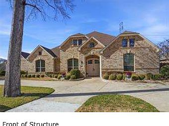 Beautiful brick exterior and double front doors with mature landscaping and a welcoming covered entry.