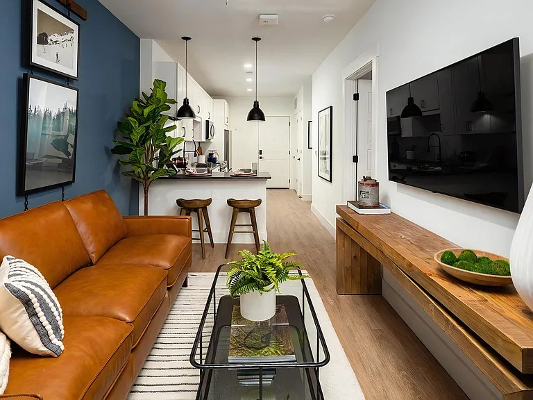 Open-concept layout with breakfast bar seating, modern lighting fixtures, and striped rug with glass coffee table