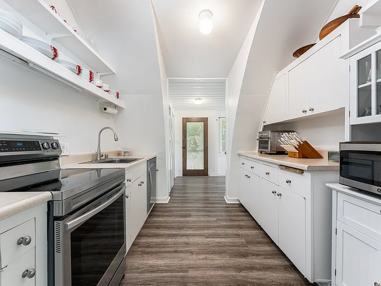Galley-style kitchen featuring ample cabinet storage, updated appliances, and luxury vinyl flooring.