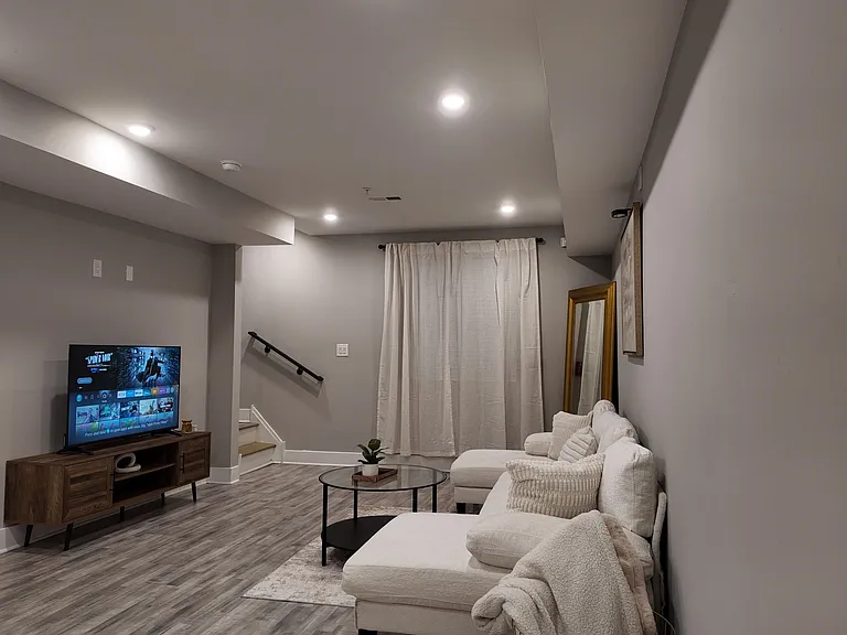 Spacious living area with recessed lighting, durable wood-look floors, and a comfortable seating zone for relaxing or streami