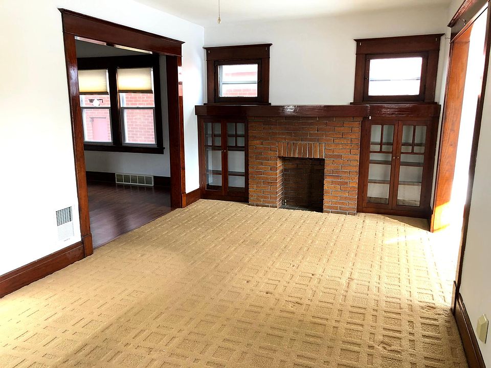 Living room with decorative fireplace and natural wood work built in glass cabinets.