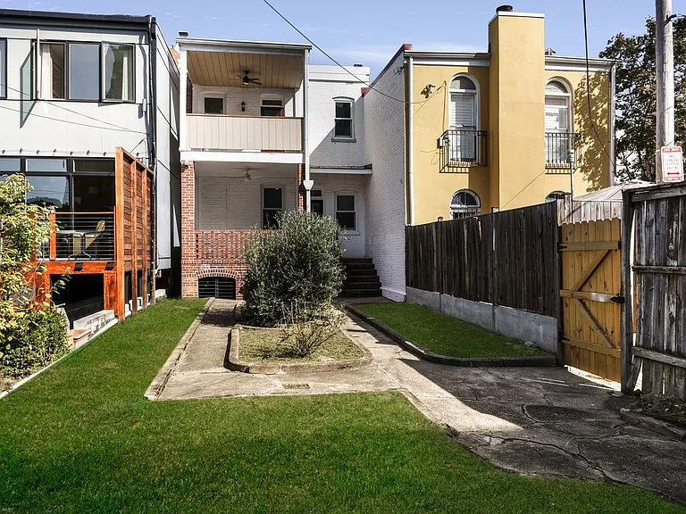 backyard with olive tree in center; upper and lower roofed decks with ceiling fan light fans