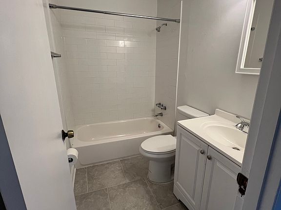 Hall bathroom with tub shower combo. Linen closet in hallway for storage.