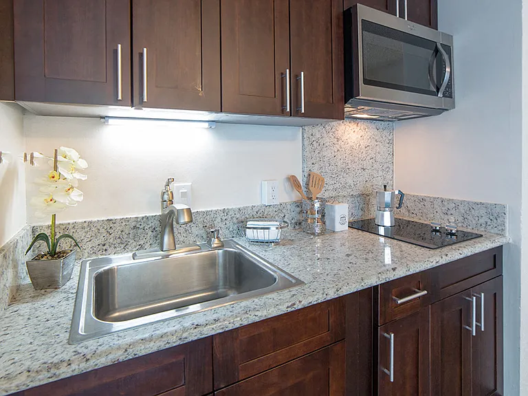 Waikiki Walina Apartments kitchen area with appliances, cabinets, and counters