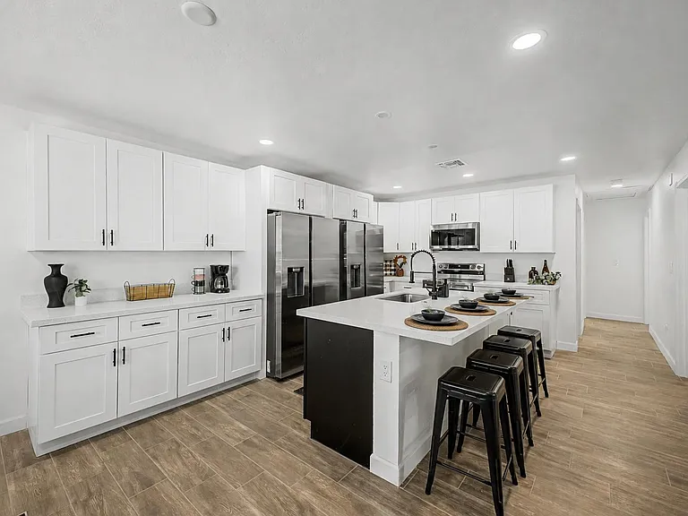Spacious kitchen with white cabinetry, stainless appliances, and a large island with seating for everyday meals.