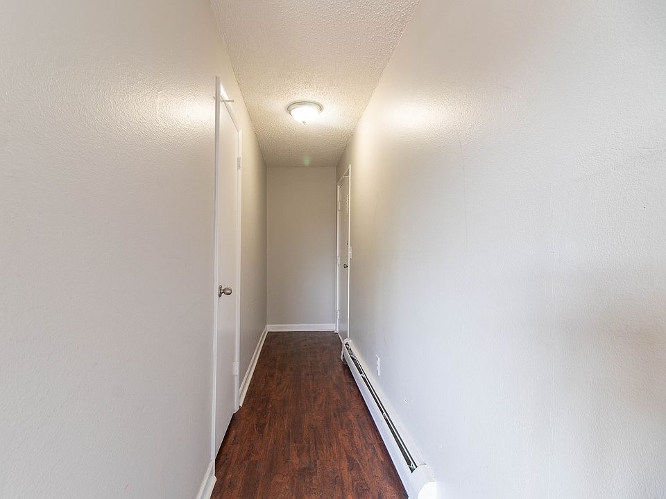 Inviting apartment hallway with modern wooden flooring and soft lighting, leading to multiple doors.