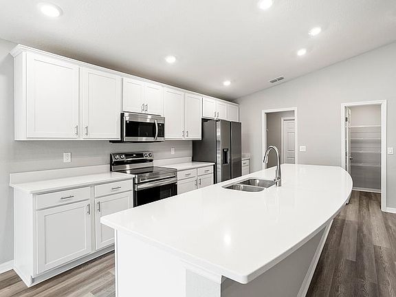 The bright, open kitchen includes a large counter-height island, walk-in pantry, and ample cabinet a