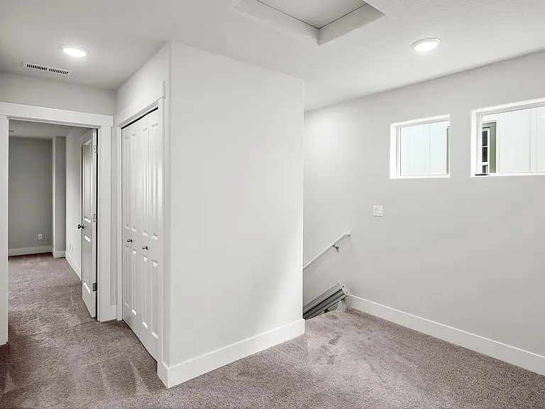Bright upper_level hallway with carpet, two windows for natural light, and access to multiple rooms plus a stairway leading down. Wash Area with stacked Washer and Dryer.