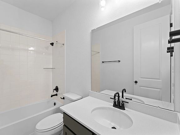 The secondary bath features tile flooring, white cabinetry and light countertops and a shower tub co