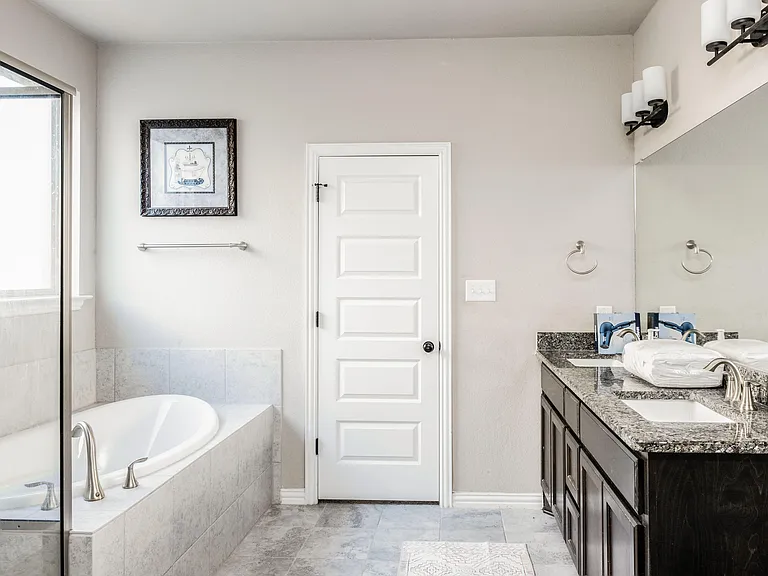 Bathroom with dual-sink vanity, granite countertop, and soaking tub/shower combo for convenient shared use.