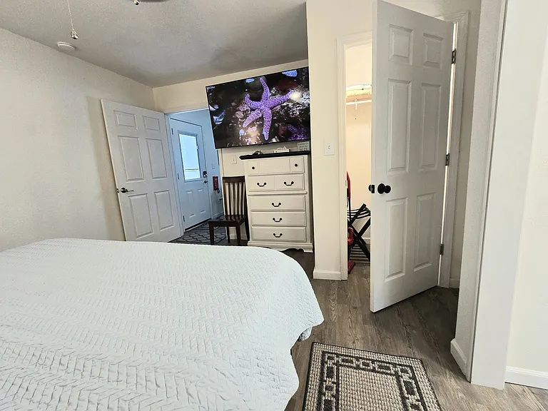 Bedroom closet, dresser, and 75" Roku TV.