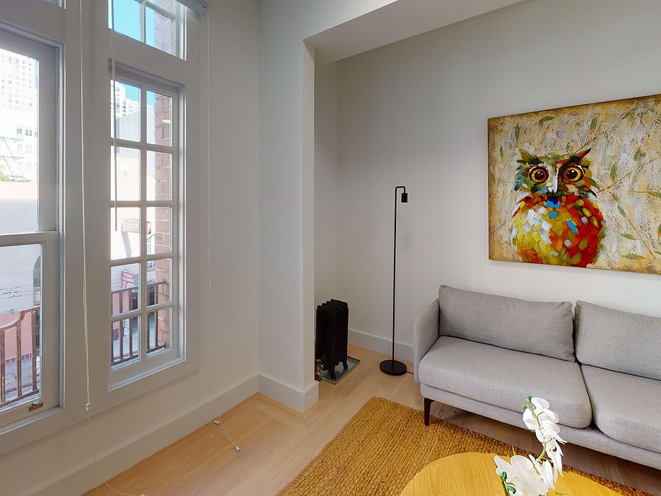 Living room with a large window offering a view of the cityscape, a wooden coffee table and sofa