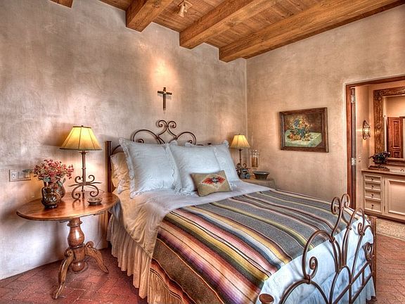 Enjoying a secluded spot off the foyer, this cozy bedroom enjoys an idyllic courtyard view & richly 