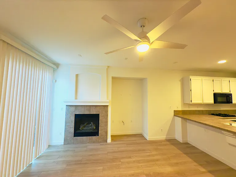 Bright and inviting living room featuring a brand-new modern fan with lights, a cozy fireplace, and a sliding door for seamless backyard access.