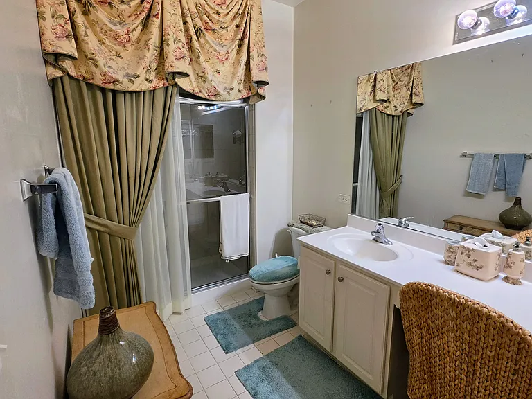 Impeccably clean secondary bathroom featuring a spacious vanity, large mirror, and full tub/shower setup.