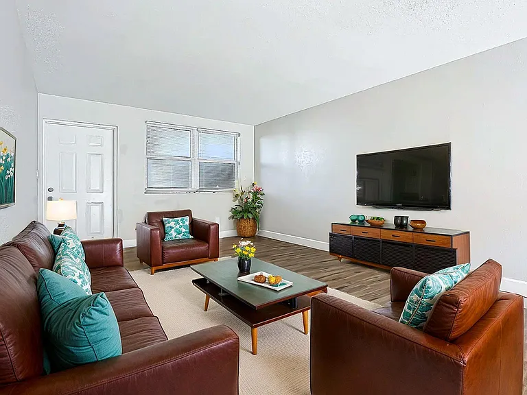 Inviting living room with stylish brown leather couches, chic decor, and modern entertainment setup, offering a cozy atmosphere. Inviting living room with stylish brown leather couches, chic decor, and modern entertainment setup, offering a cozy atmospher