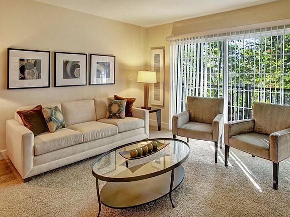 Living room with couch, table, and entertainment center with large sliding glass doors leading out to the balcony