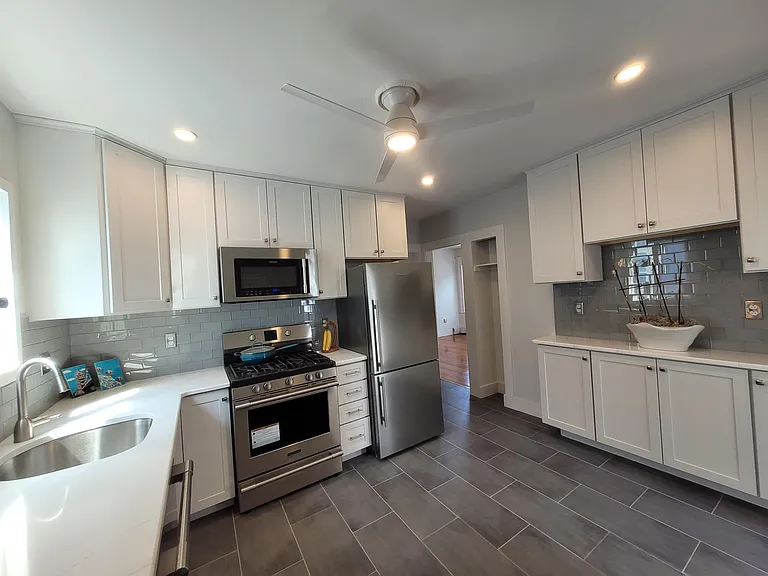 Kitchen. White ceiling height shaker cabinets, tiled floor, tiled backsplash, stone countertops, professional grade appliances.