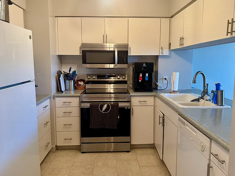 Kitchen with new stove, microwave and fridge. Also has a dishwasher and dual tub sink. Overlooks the living room and wall to wall views of Makaha