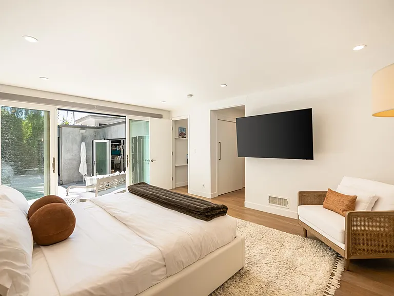 Experience comfort and convenience in the first bedroom, with glass doors sliding open to the outdoors.