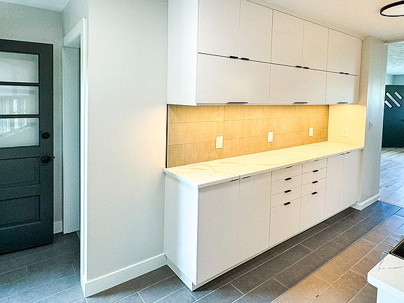 Kitchen with new everything - stainless steel appliances, quartz countertops, cabinets, lighting, tile floor and backsplash.