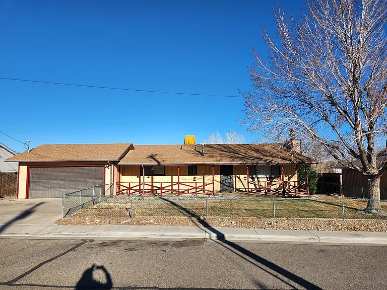 Front entry level of house with two car garage and fenced yard.