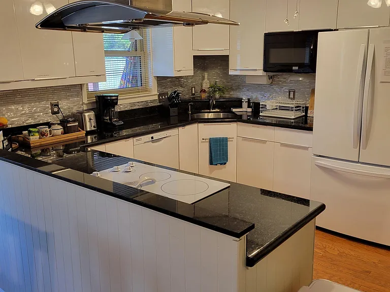 The kitchen features a stove, oven, ventilation hood, dishwasher, garbage disposal, microwave and refrigerator with freezer and ice maker. The kitchen has pots, pans, dishes, drinking cups, flatware and utensils.