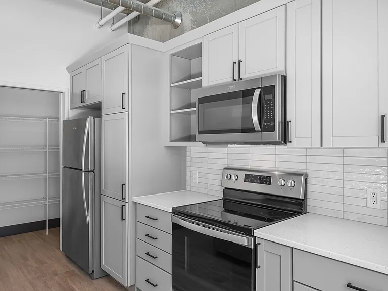 Modern kitchen featuring sleek stainless steel appliances, elegant white cabinetry, and a spacious pantry. Modern kitchen featuring sleek stainless steel appliances, elegant white cabinetry, and a spacious pantry.