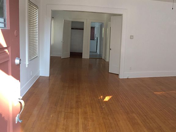 The entryway opens to a large and versatile living space, accented by original hardwood flooring throughout .