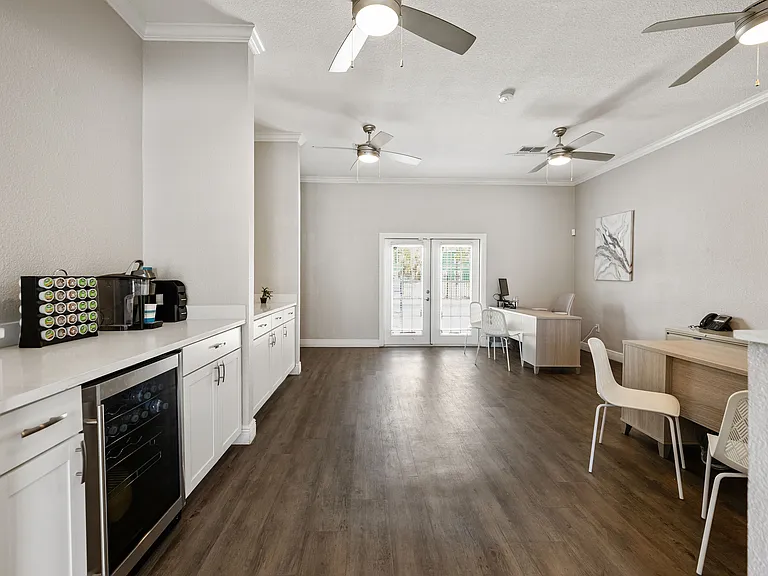 Sleek modern interior with elegant white cabinetry, gleaming wood floors, and ample natural light through double French doors.