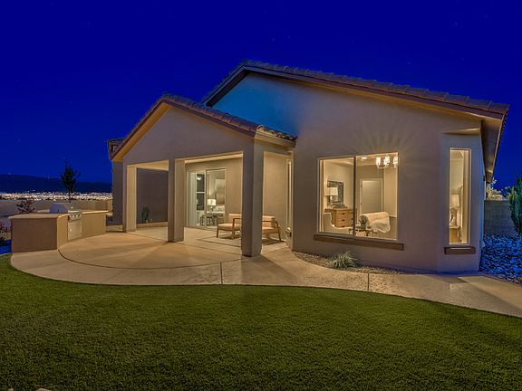 Twilight exterior of the Hewitt backyard showing a covered patio and a combination of grass and conc