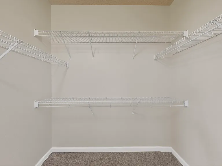 The large primary bedroom walk in closet features plenty of space and organization.