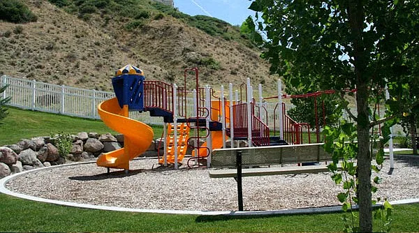 Liberty Hill Apartments, Draper, Utah, playground with a yellow slide and a red and white fence.