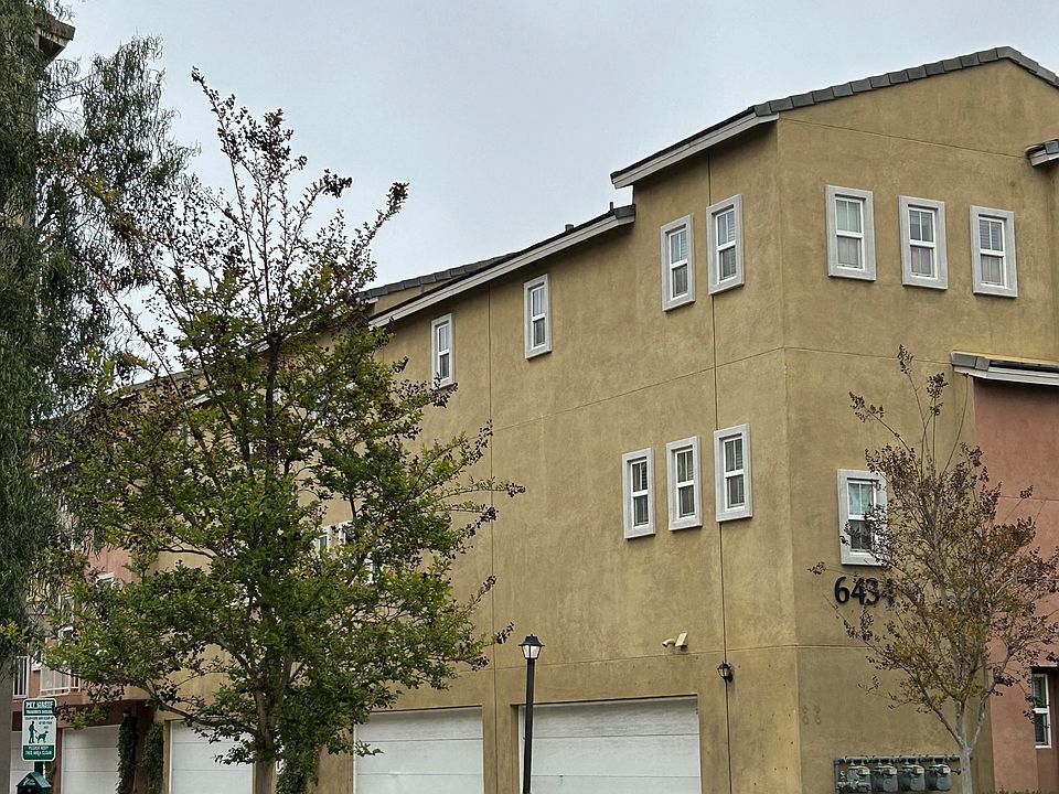 Attached two-car garages and gas barbeques amongst garden landscape at Serenata Townhomes in San Diego, California.
