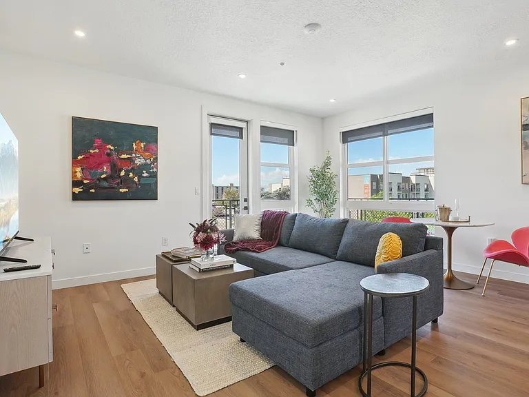 Liberty Duet Apartments, Salt Lake City, Utah; A living room with a grey couch and a red chair.