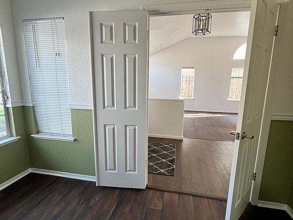 View from fourth bedroom/Office past entryway and into living dining area. Located at front of house.