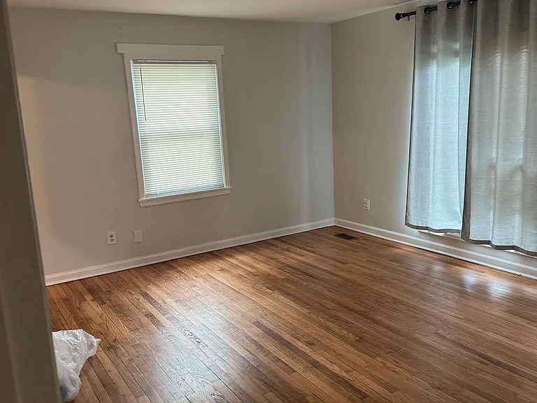 Living room with polished hardwood floors along with picture window and side window.