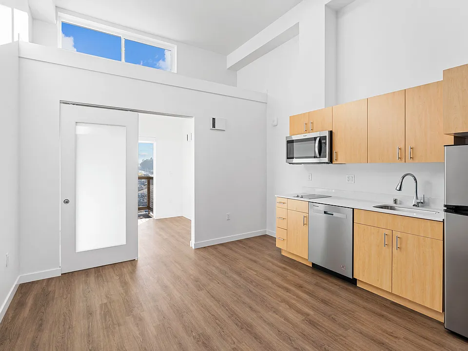 Enjoy cooking in this modern kitchen featuring sleek wood flooring, ample cabinet space, and a clean, open design.