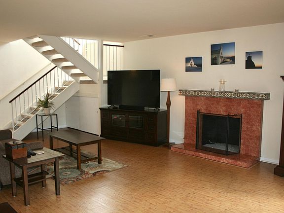 Living room with gas tiled fireplace and mantle. Bamboo flooring. Carpeted stairs.