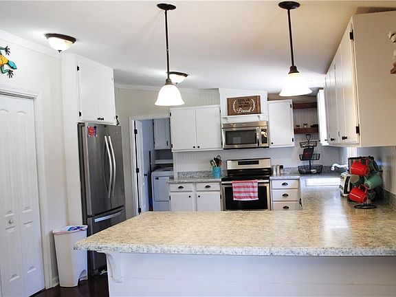 The kitchen features custom cabinets and countertops. A large pantry with wood shelving and stainless appliances. Hardwood floors throughout the kitchen.