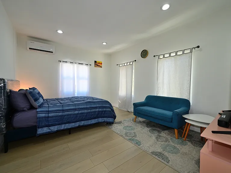 Super spacious bedroom furnished with TV, queen bed and mattress, mini split AC, Loveseat and Coffee table - with views of PCC