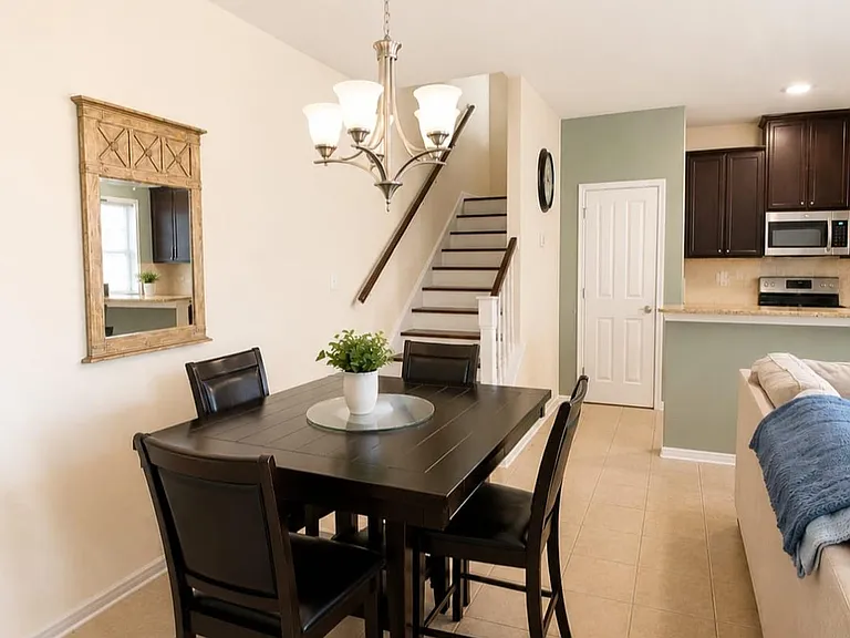 Dining area with a table for four, chandelier lighting, and easy access to the kitchen and main living space.