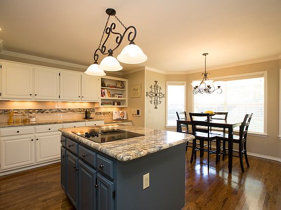 Beautifully updated Kitchen offers exotic granite, center island with electric cooktop and storage, hardwood floors, travertine backsplash with glass tile inserts, full pantry and convenient planning desk.