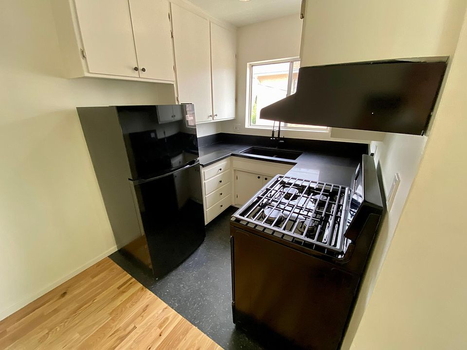 Kitchen including refrigerator, gas stove, range hood.
