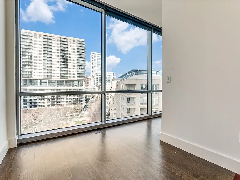 Spare room featuring dark wood-type flooring, a city view, and expansive windows