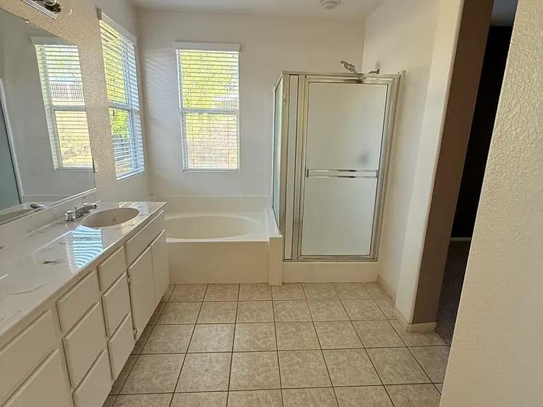 Bathroom in primary room. Tub, shower, two sinks, separate room with toilet.